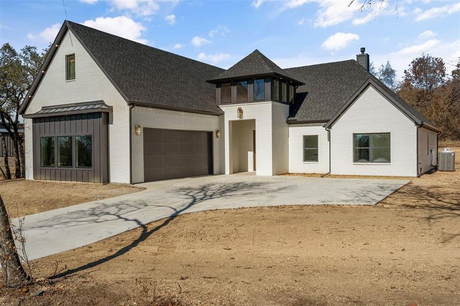 View of front of house with central AC, a balcony, and a garage