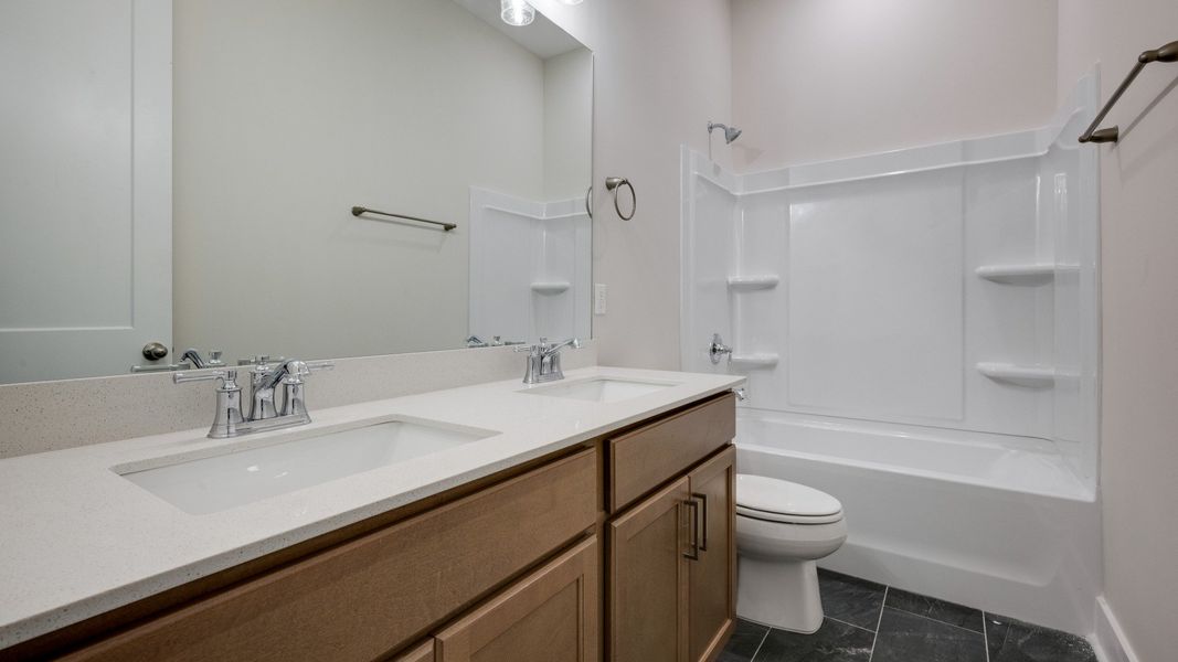 Secondary bathroom with elevated features such as dual vanities and bathtub