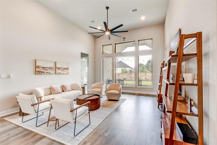 A spacious living area features high ceilings and abundant natural light through towering windows.