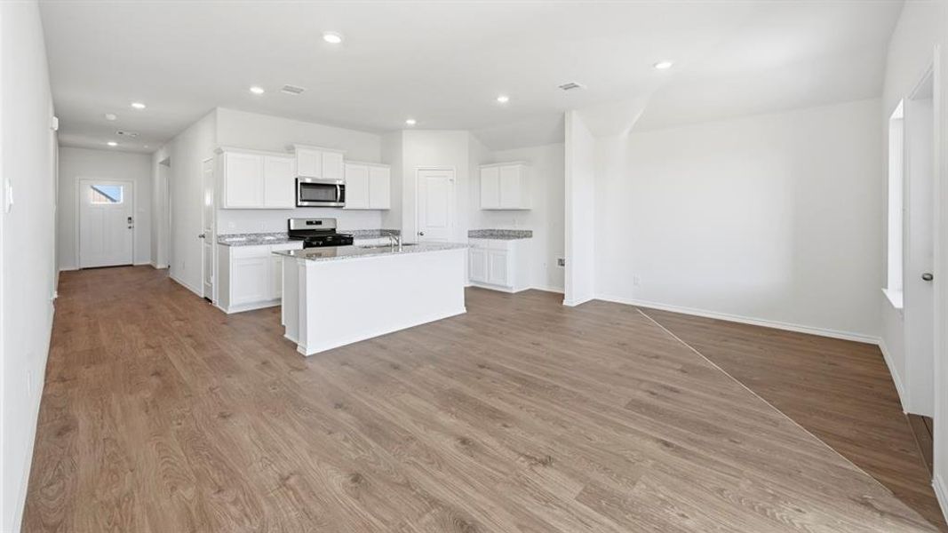Kitchen with white cabinetry, appliances with stainless steel finishes, light wood-style floors, an island with sink, and recessed lighting Kitchen with white cabinetry, appliances with stainless steel finishes, light wood-style floors, an island with sink, and recessed lighting