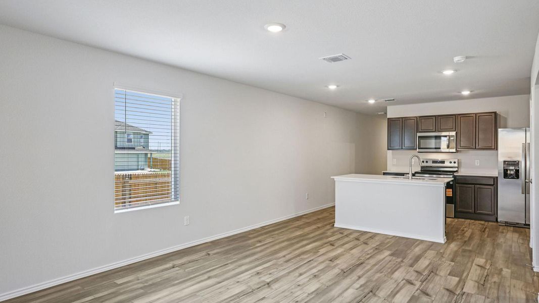 Kitchen featuring stainless steel appliances, recessed lighting, light wood-style floors, a center island with sink, and dark wood finish cabinetry