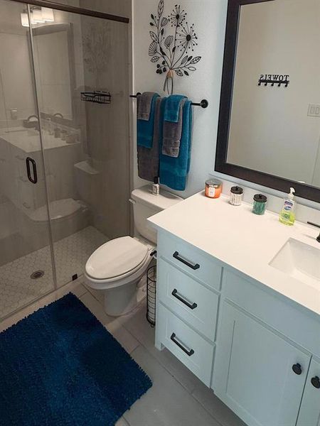Bathroom featuring light tile patterned floors, vanity, and a stall shower Bathroom featuring light tile patterned floors, vanity, and a stall shower