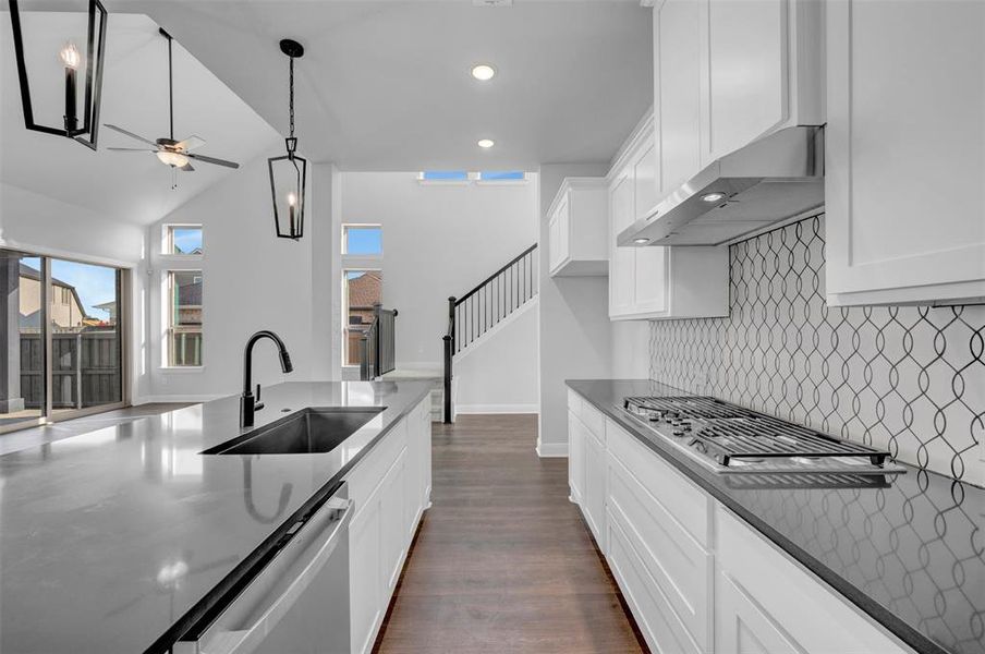 Kitchen featuring white cabinets, dark stone countertops, ceiling fan, dark wood-style flooring, and stainless steel appliances Kitchen featuring white cabinets, dark stone countertops, ceiling fan, dark wood-style flooring, and stainless steel appliances