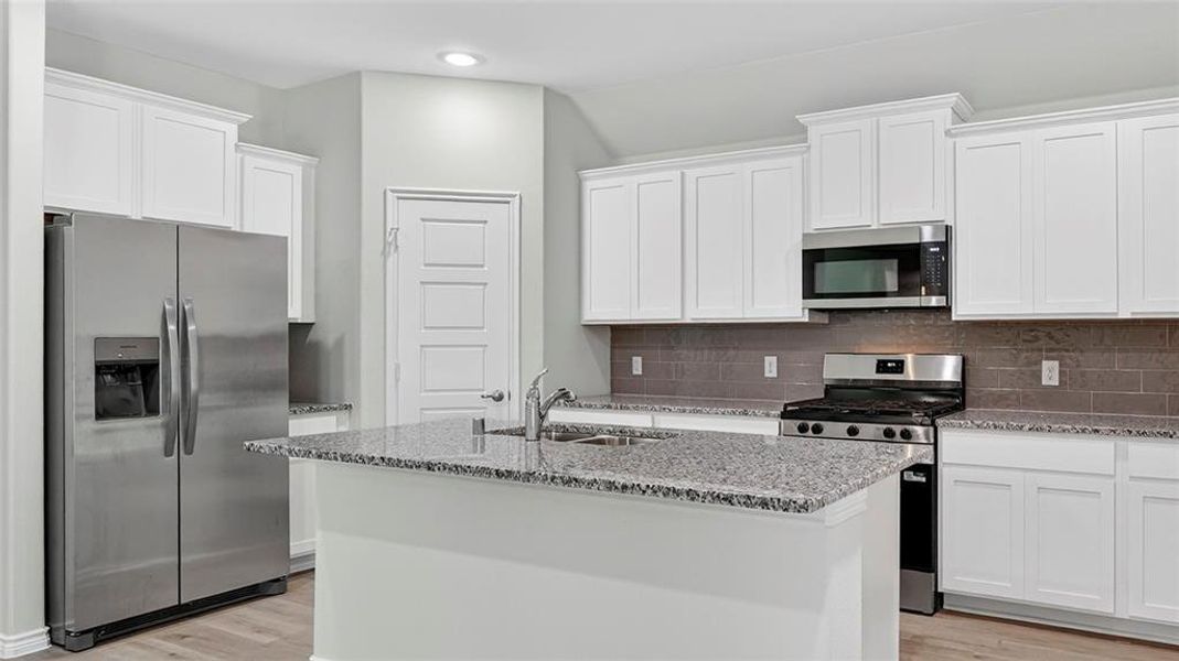 Kitchen with a central island featuring a stainless steel double-basin sink and a gooseneck faucet