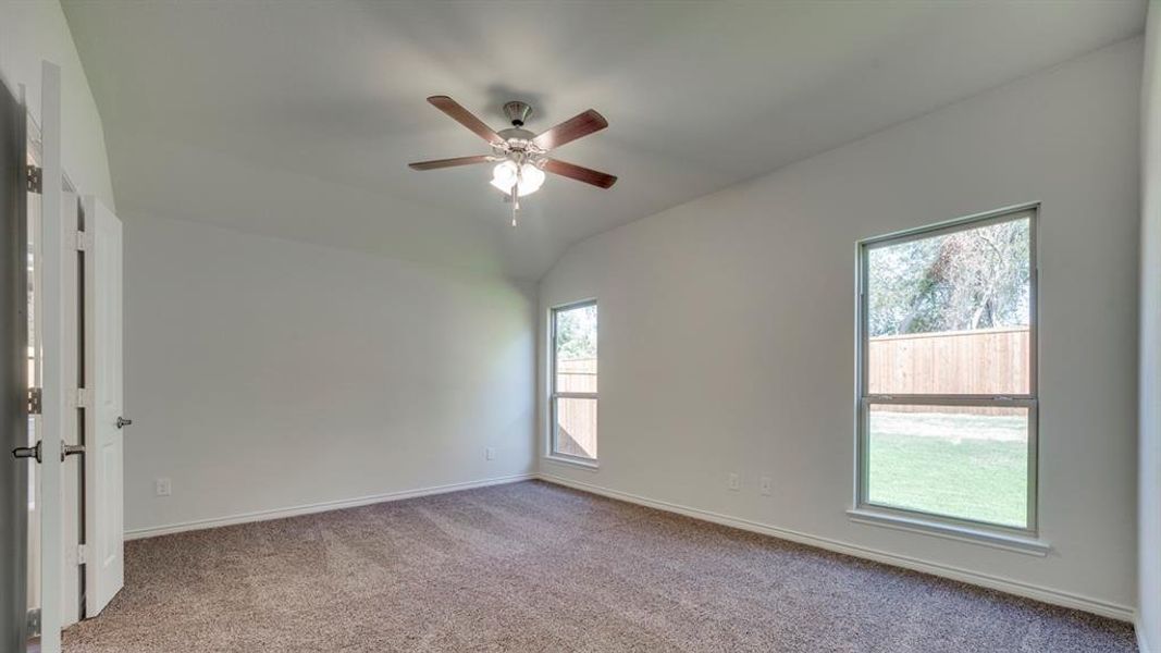 Empty room with carpet flooring, a ceiling fan, and vaulted ceiling