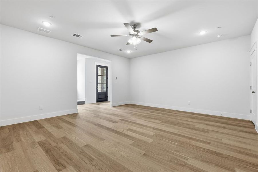 This spacious room features light wood flooring, white walls, and recessed lighting