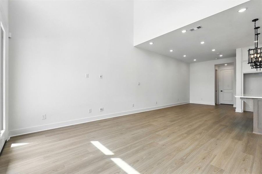 Unfurnished living room featuring recessed lighting, light wood-style flooring, and a chandelier Unfurnished living room featuring recessed lighting, light wood-style flooring, and a chandelier