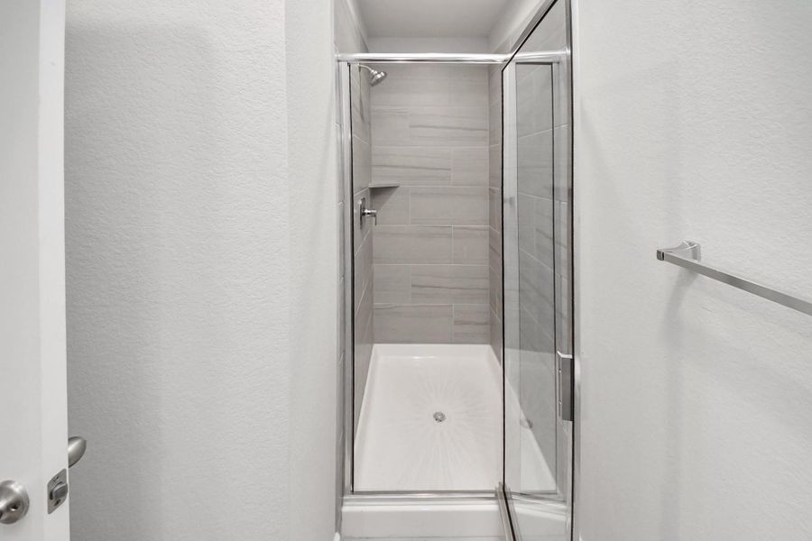 Walk-in shower with floor-to-ceiling tile surround and a glass enclosure, part of the fourth bedroom’s private ensuite bathroom.