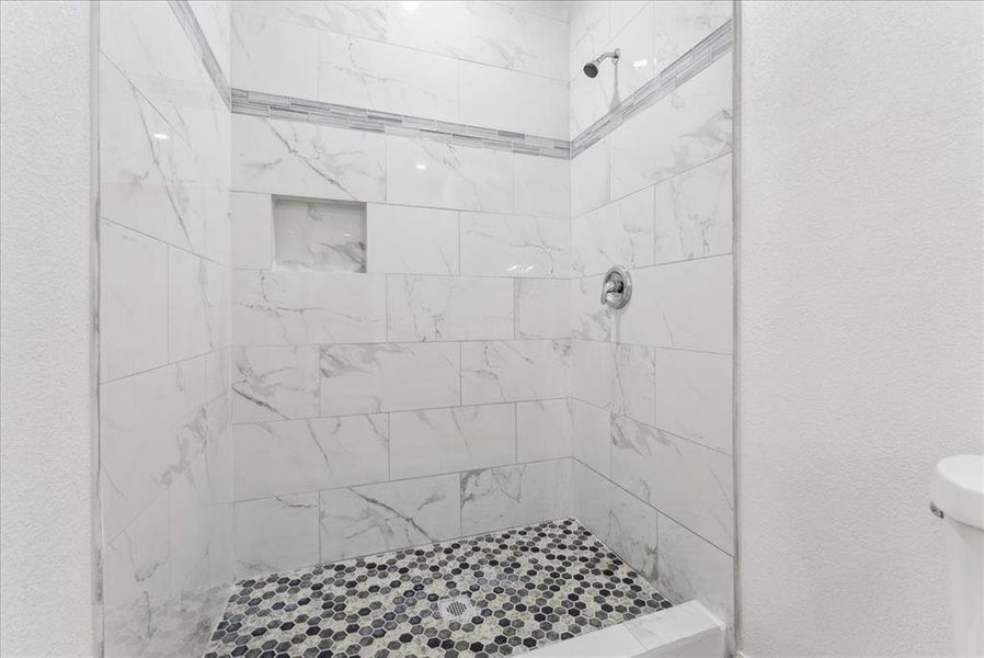 Full bathroom with tiled shower and a textured wall