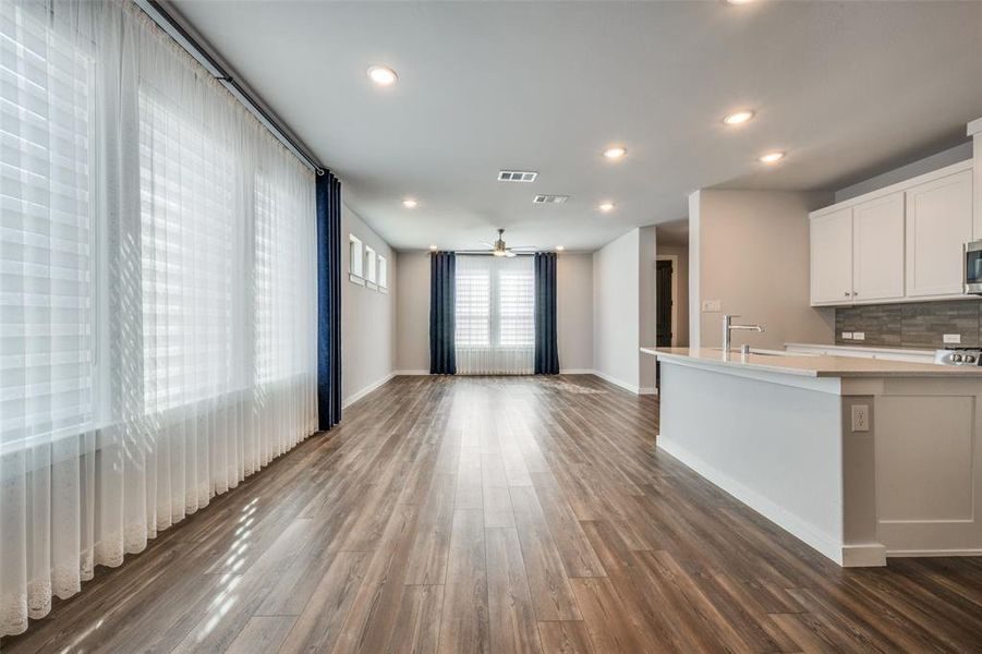 Kitchen featuring tasteful backsplash, dark wood-type flooring, light countertops, recessed lighting, and white cabinetry