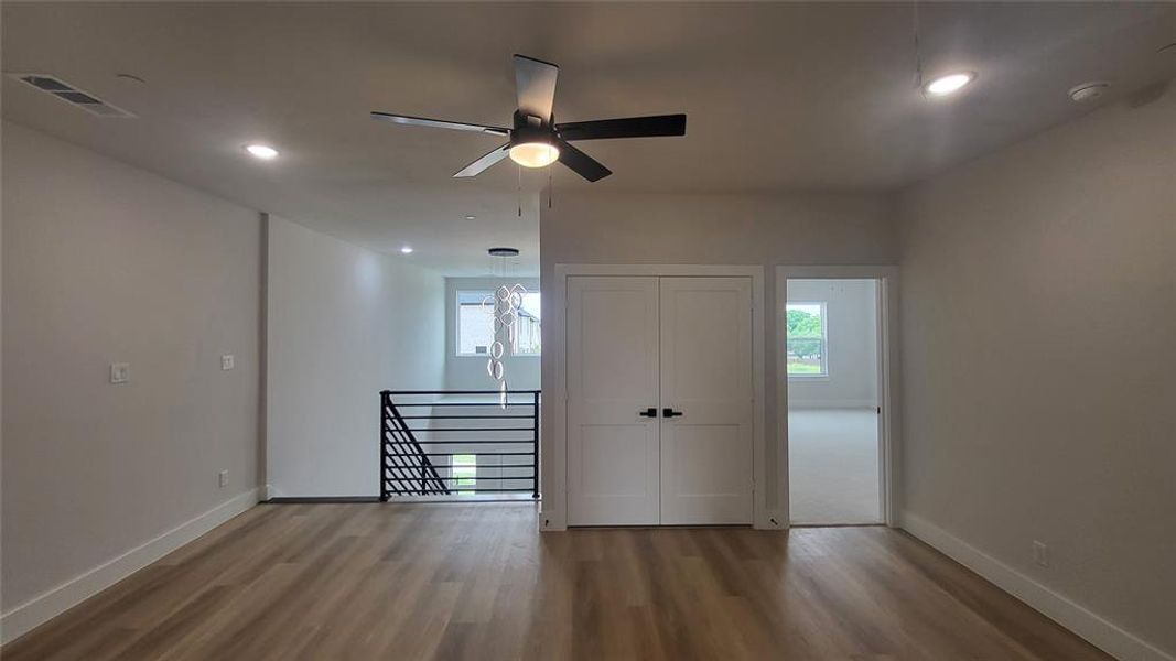 Empty room with baseboards, wood finished floors, visible vents, and a ceiling fan