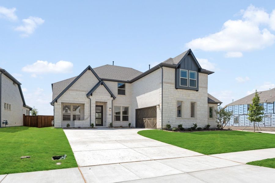 Two-story home with light brick and stone exterior, dark trim, single-car garage, and concrete driveway with green lawn.