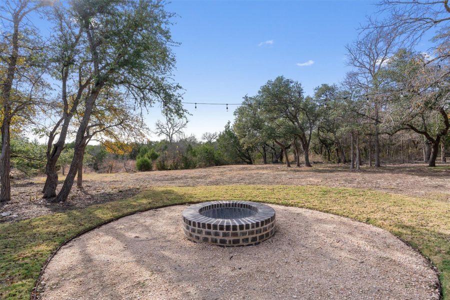 A private backyard setting with a built-in fire pit and covered patio, ideal for relaxing evenings and gathering under the trees. A private backyard setting with a built-in fire pit and covered patio, ideal for relaxing evenings and gathering under the trees.