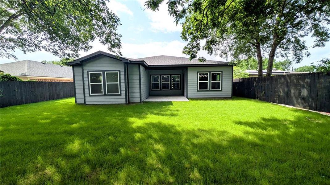 Rear view of property with a fenced backyard, a yard, and a patio area