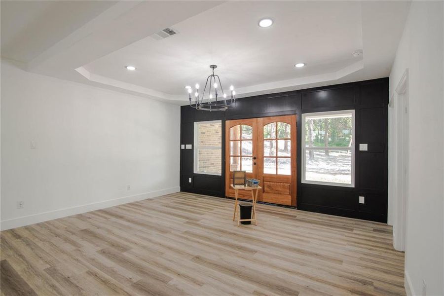 Unfurnished room with a tray ceiling, french doors, and light hardwood / wood-style flooring