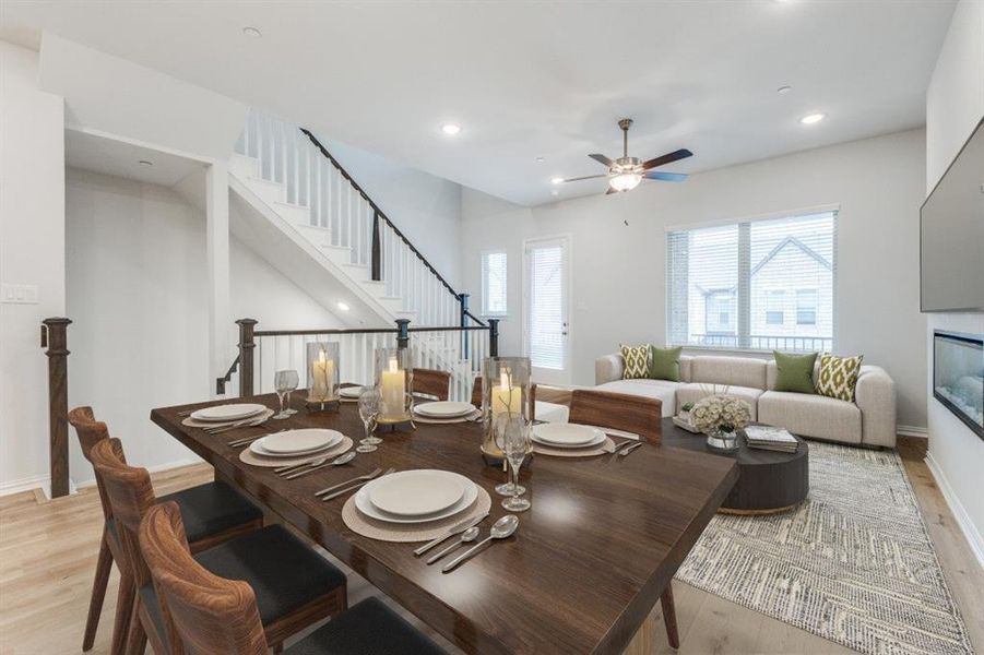 Dining area featuring light wood-type flooring, plenty of natural light, a glass covered fireplace, and stairway