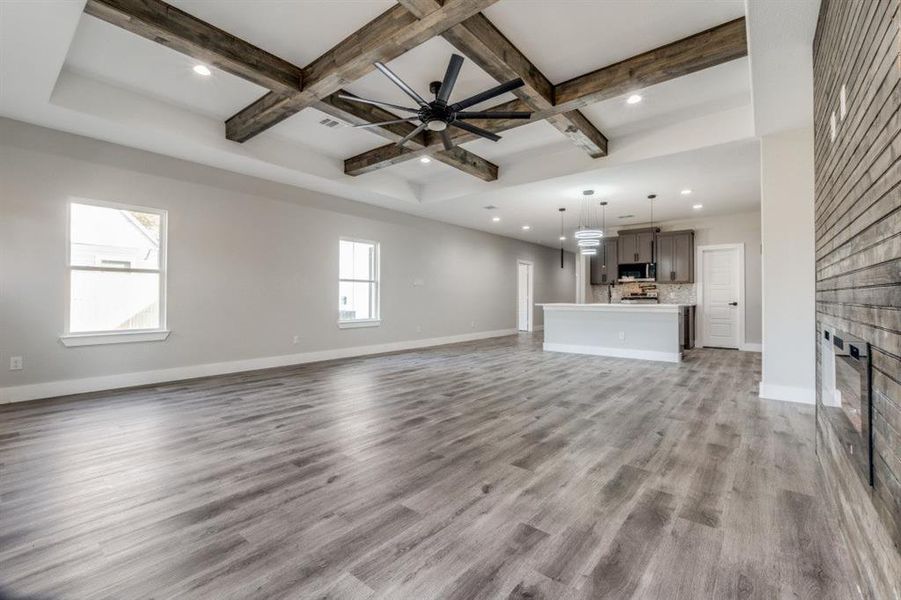 Unfurnished living room with beam ceiling, light wood-type flooring, and ceiling fan