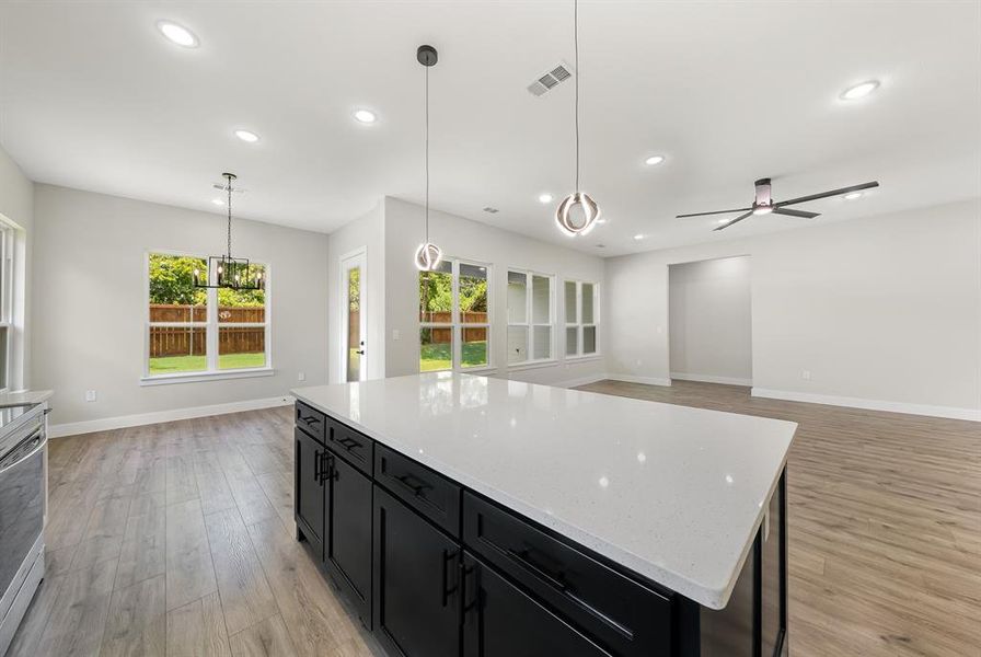 Kitchen featuring dark cabinets, light wood finished floors, recessed lighting, ceiling fan, and open floor plan Kitchen featuring dark cabinets, light wood finished floors, recessed lighting, ceiling fan, and open floor plan