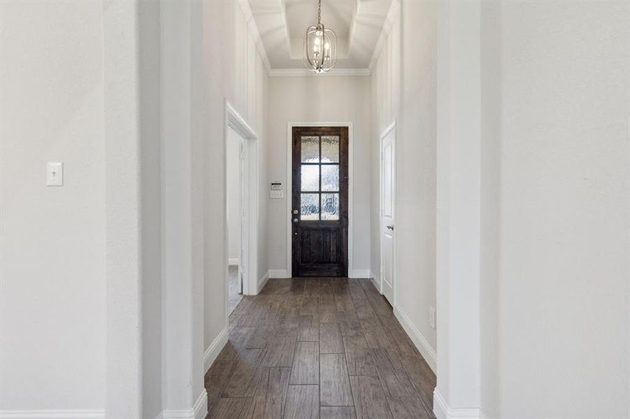 Entryway with ornamental molding, hardwood / wood-style flooring, and illuminating chandelier. Entryway with ornamental molding, hardwood / wood-style flooring, and illuminating chandelier.