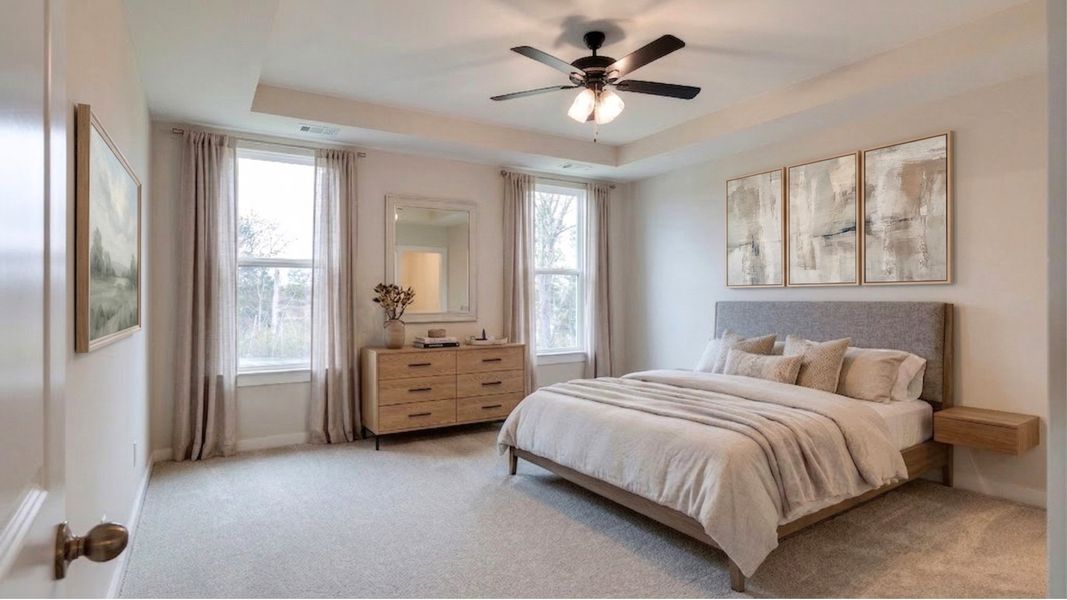 Virtually staged primary bedroom with tray ceiling and natural light from windows