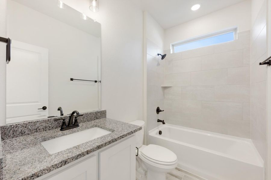 Full bathroom with granite vanity, white cabinets, and tiled tub-shower combo with small window above Full bathroom with granite vanity, white cabinets, and tiled tub-shower combo with small window above