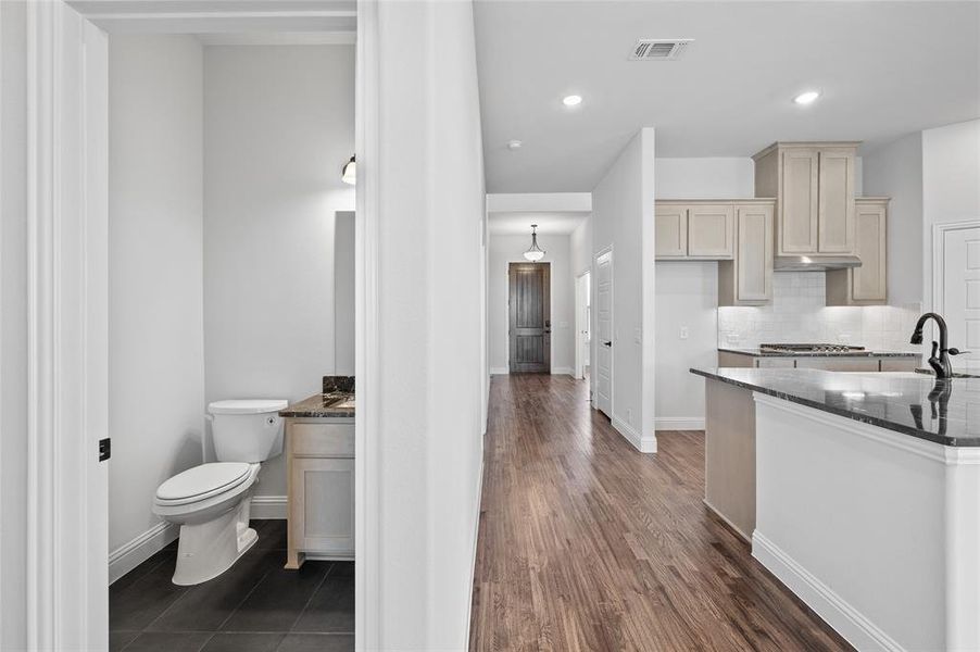 Kitchen with dark stone countertops, tasteful backsplash, recessed lighting, and dark wood-type flooring