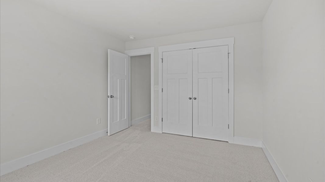 Carpeted secondary bedroom with walk-in closet in two story townhome at Aspen Ridge by DRB Homes in Lyman, SC Carpeted secondary bedroom with walk-in closet in two story townhome at Aspen Ridge by DRB Homes in Lyman, SC