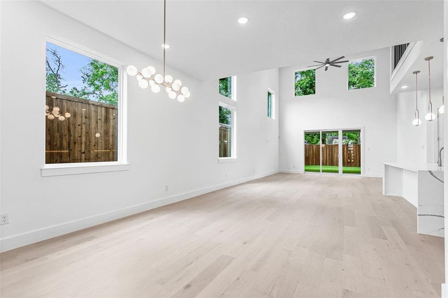 Unfurnished living room with plenty of natural light, a ceiling fan, light wood-style floors, baseboards, and recessed lighting