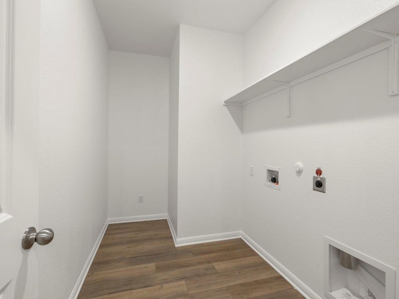 A well-organized utility room offers ample space for laundry, featuring convenient hookups and overhead shelving.