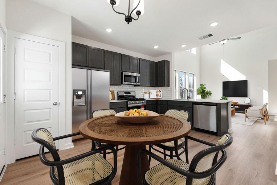 From the dining section, enjoy views of the kitchen's pantry, sleek dark gray cabinetry, quartz countertops, and stainless steel appliances, including a large refrigerator, gas range, microwave and dishwasher. *Virtually Staged From the dining section, enjoy views of the kitchen's pantry, sleek dark gray cabinetry, quartz countertops, and stainless steel appliances, including a large refrigerator, gas range, microwave and dishwasher. *Virtually Staged