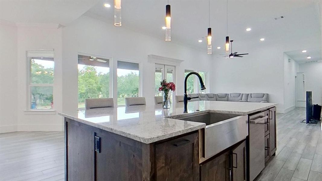 Kitchen island featuring a farmhouse sink, granite countertops, and dark wood cabinetry Kitchen island featuring a farmhouse sink, granite countertops, and dark wood cabinetry