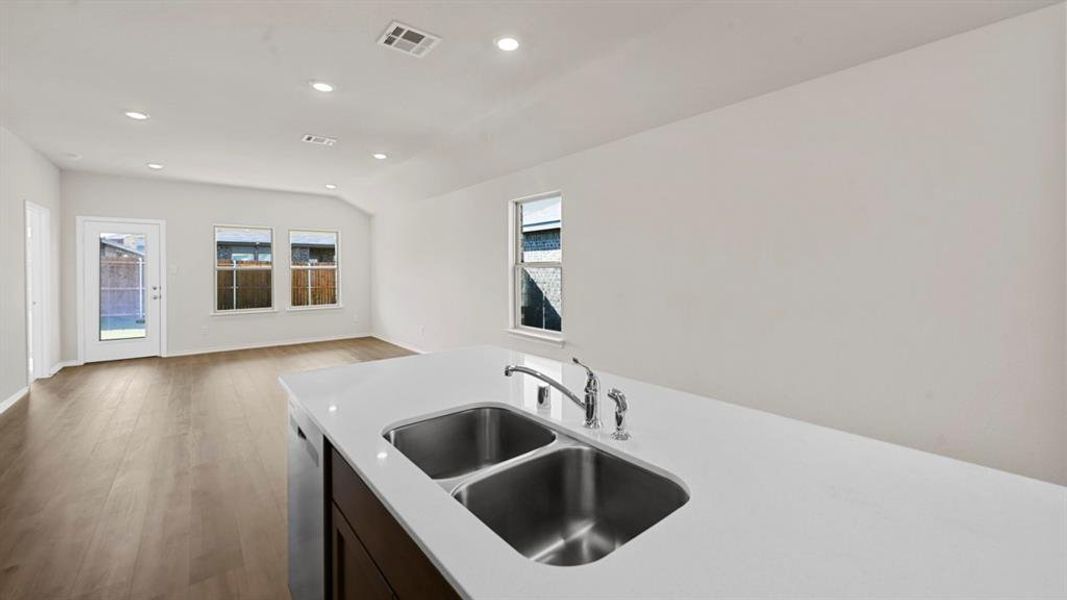 Kitchen with recessed lighting, dark wood finished floors, dark wood finish cabinetry, dishwasher, and light stone countertops