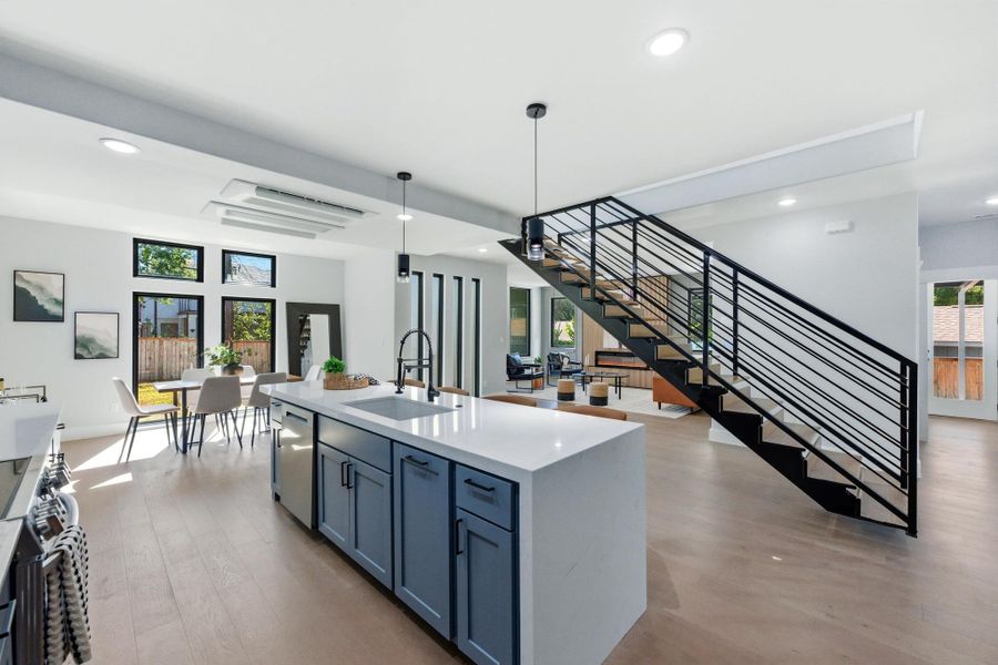 Kitchen featuring recessed lighting, hanging light fixtures, light wood-style flooring, light stone countertops, and appliances with stainless steel finishes Kitchen featuring recessed lighting, hanging light fixtures, light wood-style flooring, light stone countertops, and appliances with stainless steel finishes