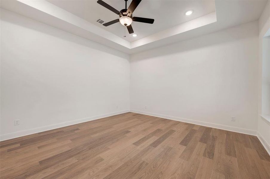 This room features light-colored walls, wood flooring, and a ceiling fan