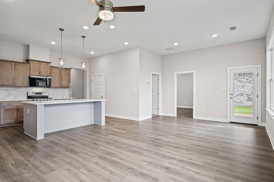 Kitchen featuring decorative backsplash, a center island with sink, pendant lighting, a ceiling fan, and recessed lighting