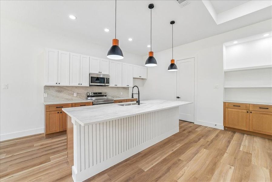 Modern kitchen featuring a large central island with a waterfall countertop, integrated sink, and matte black faucet Modern kitchen featuring a large central island with a waterfall countertop, integrated sink, and matte black faucet