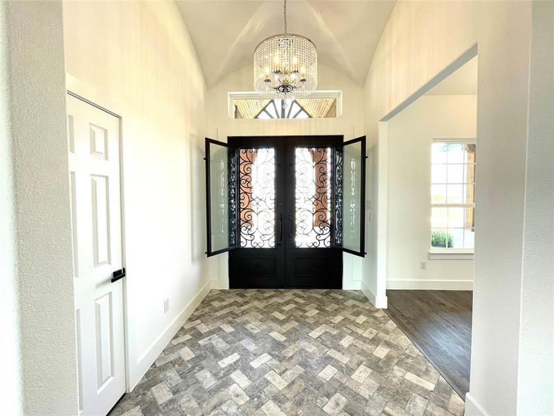 Entrance foyer with a chandelier, lofted ceiling, and french doors Entrance foyer with a chandelier, lofted ceiling, and french doors