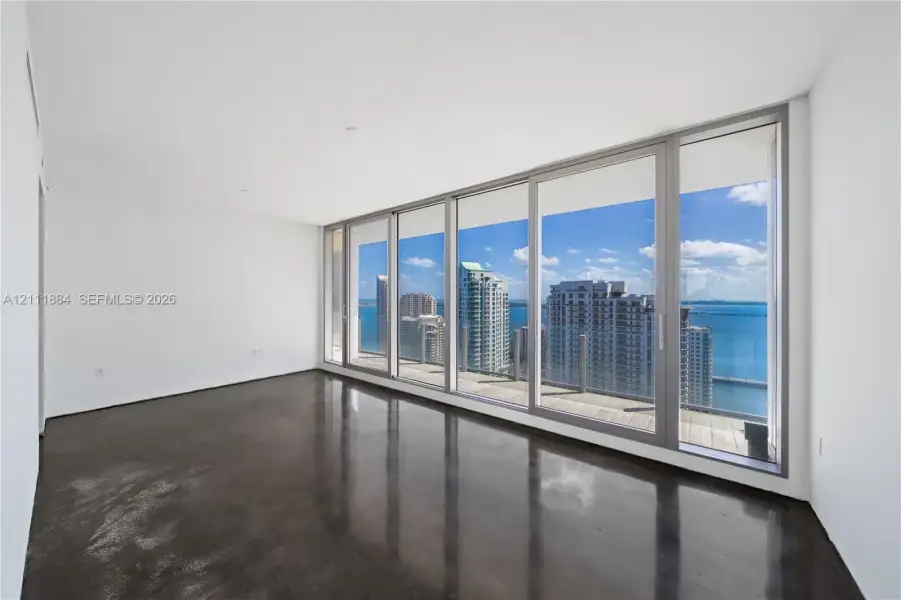 Floor-to-ceiling windows, polished concrete flooring, recessed lighting, and a glass-railed balcony with a coastal skyline backdrop Floor-to-ceiling windows, polished concrete flooring, recessed lighting, and a glass-railed balcony with a coastal skyline backdrop