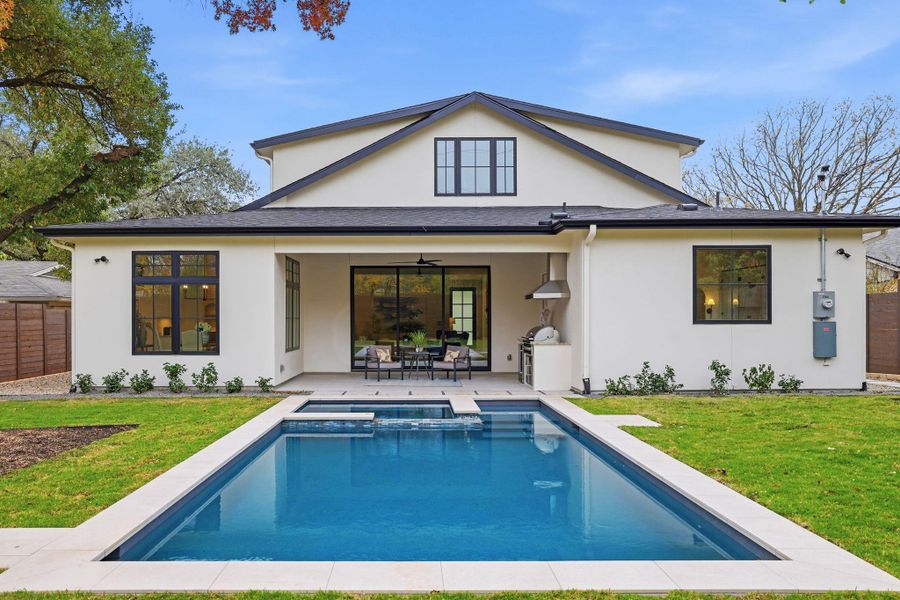 Rear view of house featuring a ceiling fan, a patio, stucco siding, and a pool with connected hot tub