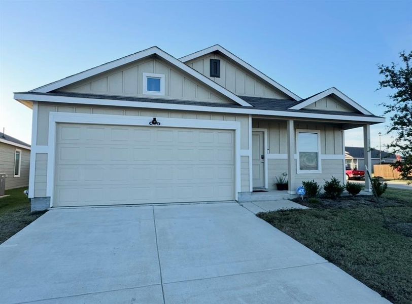 View of front facade with board and batten siding, driveway, a front yard, and a shingled roof
