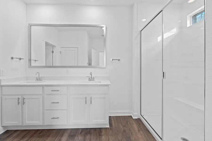 Bathroom with a stall shower, double vanity, and dark wood-style flooring Bathroom with a stall shower, double vanity, and dark wood-style flooring