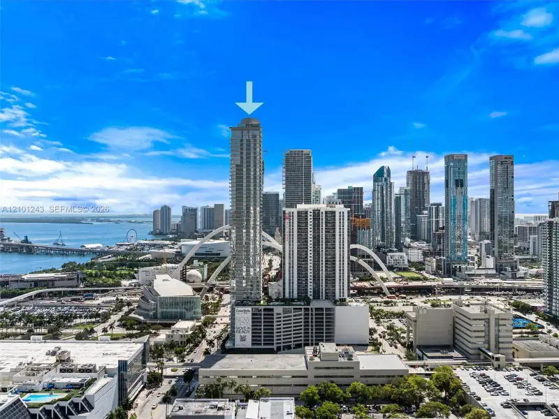 High-rise residential tower featuring a concrete facade, multiple private balconies, and a multi-level structured parking garage High-rise residential tower featuring a concrete facade, multiple private balconies, and a multi-level structured parking garage