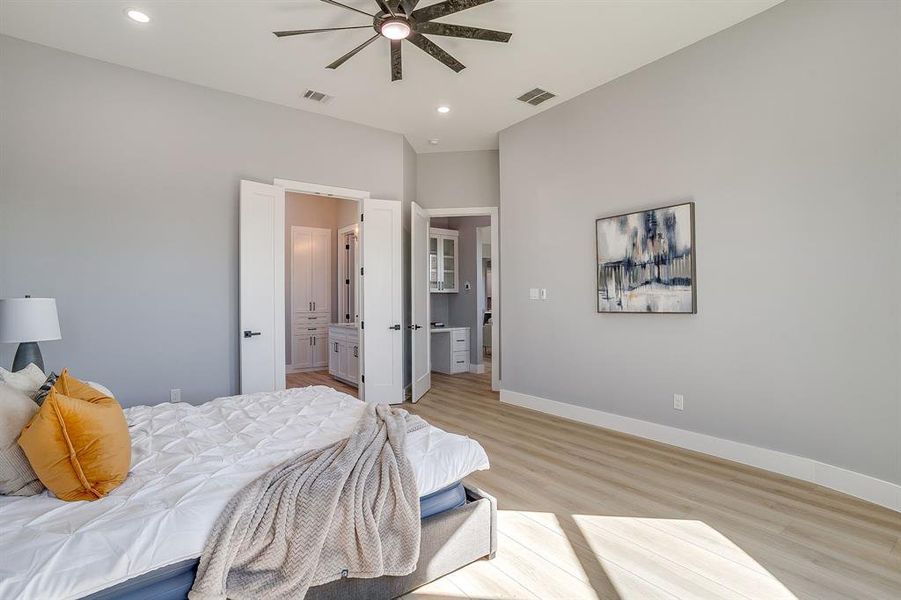 Bedroom with light wood finished floors, connected bathroom, recessed lighting, and ceiling fan