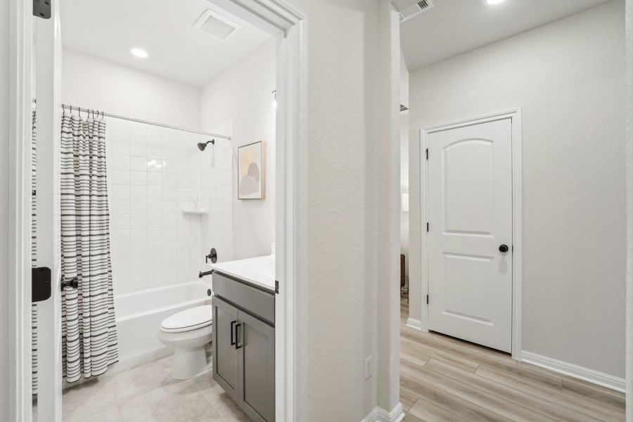 Bathroom featuring visible vents, wood finished floors, shower / tub combo, and vanity