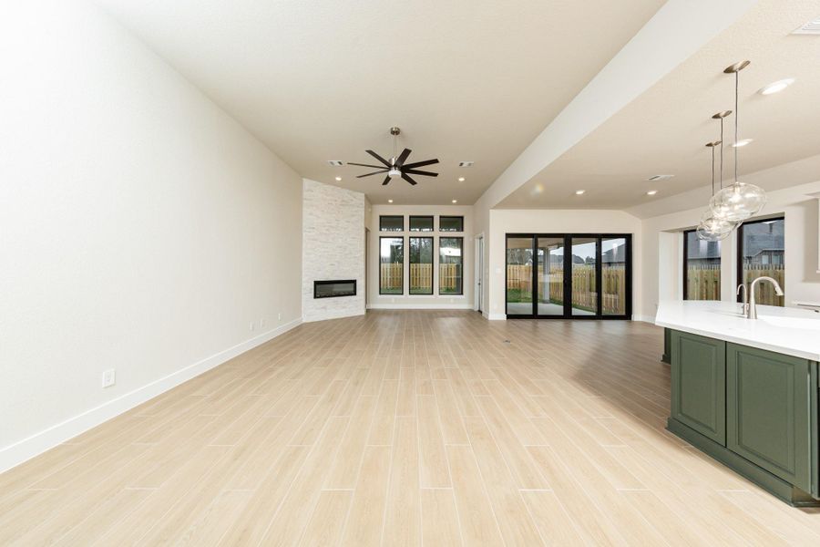 Enjoy an open, airy living experience! The Great Room features a stunning electric fireplace with stacked stone - floor to ceiling. The oversized windows flood the entire space with abundant natural light and frame a picturesque view of the serene backyard. A large ceiling fan provides comfort all year long. Enjoy an open, airy living experience! The Great Room features a stunning electric fireplace with stacked stone - floor to ceiling. The oversized windows flood the entire space with abundant natural light and frame a picturesque view of the serene backyard. A large ceiling fan provides comfort all year long.
