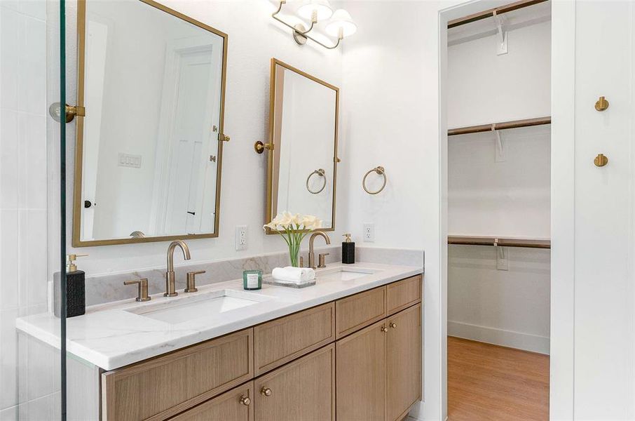 Full bath with double vanity, a spacious closet, and light wood-style flooring