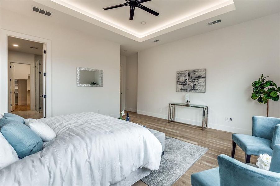 Bedroom featuring a tray ceiling, ceiling fan, and light hardwood / wood-style flooring