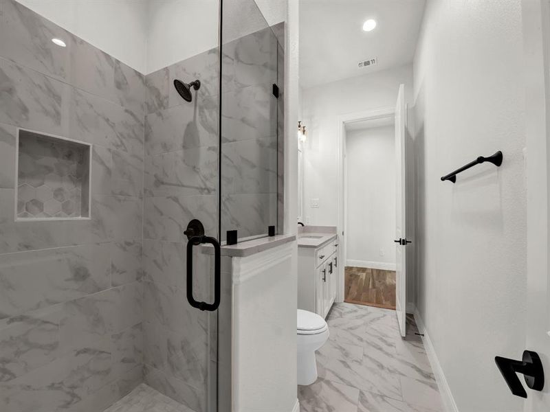 Bathroom featuring vanity, toilet, and an enclosed shower