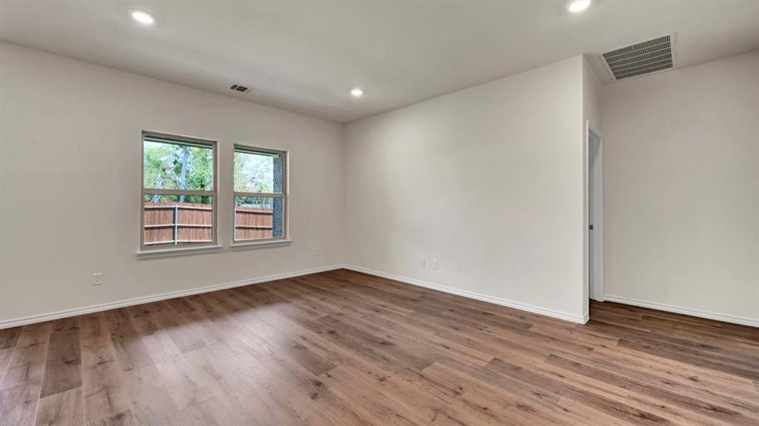 Spacious room featuring wood-finish flooring, recessed lighting, and two double-hung windows