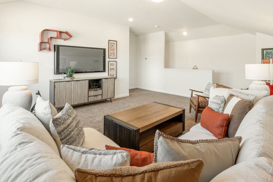 Upstairs bonus room with sectional sofa, wood coffee table, and wall-mounted TV on carpet